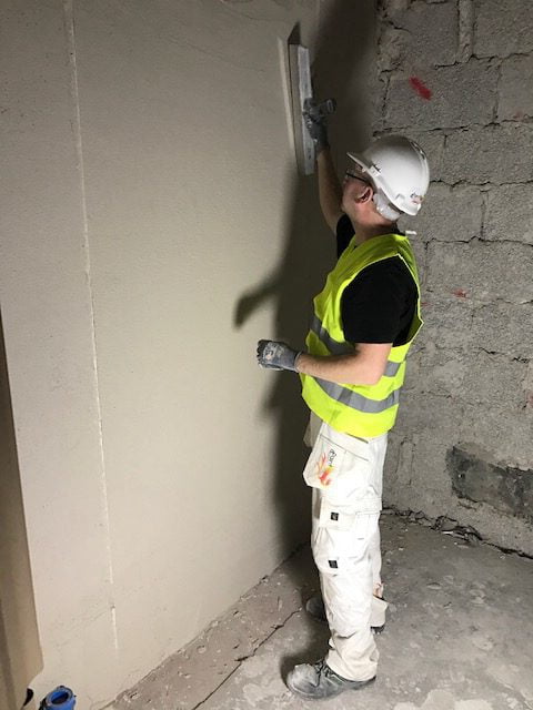 Hantverkare anlägger gips på vägg